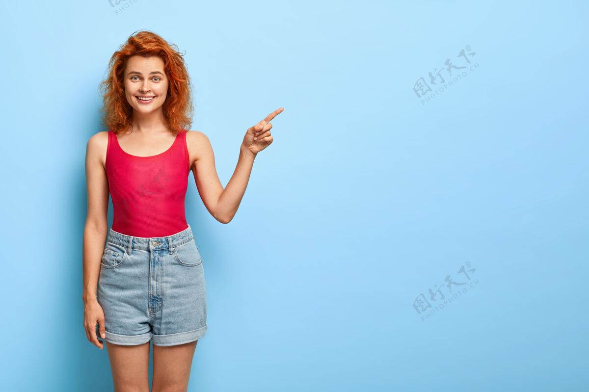 秀快乐开朗的女人 身材苗条 指着右边的空白处 广告酷的对象食指指点青少年