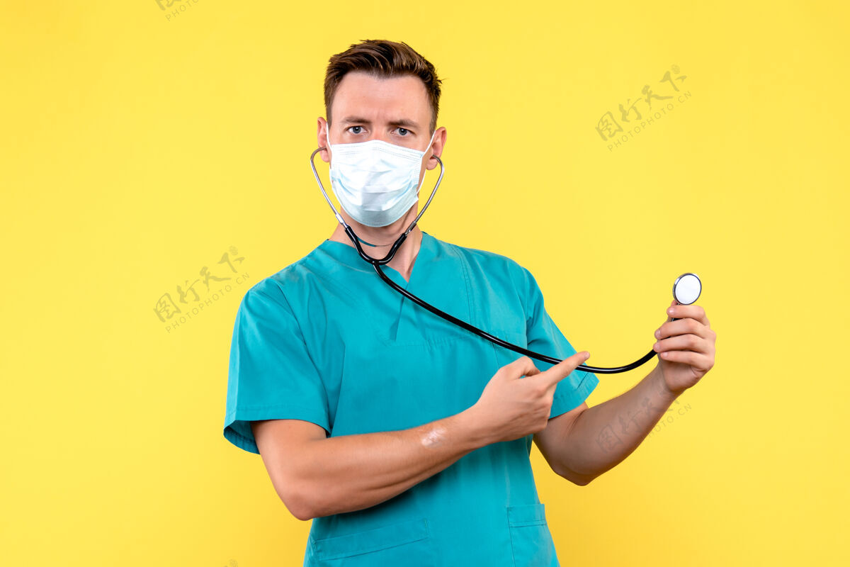 专业黄色地板上戴着面罩和眼压计的男医生的正面图情感医院医生面具医生男医生