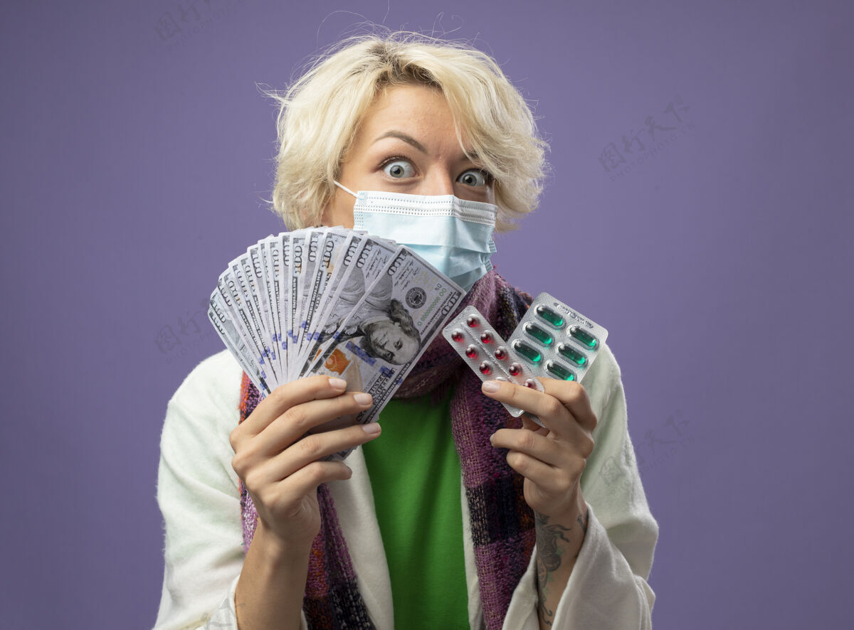 温暖生病的不健康的女人 短发 戴着暖和的围巾和面罩 手里拿着现金和水泡 手里拿着药片 站在紫色的墙上 焦虑和困惑担心抱着头发