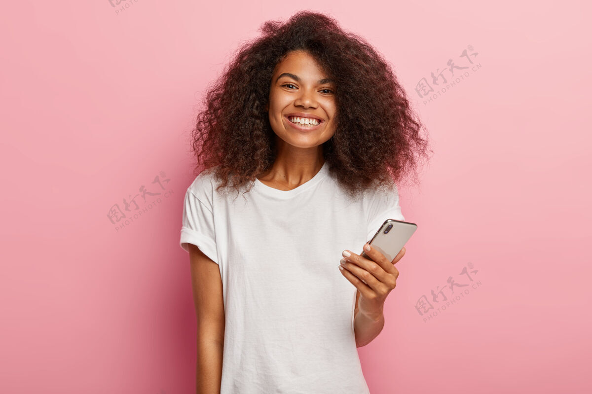 千禧一代令人印象深刻的可爱的非洲女人豪华卷发 手持现代手机 等待来电乐观女性检查