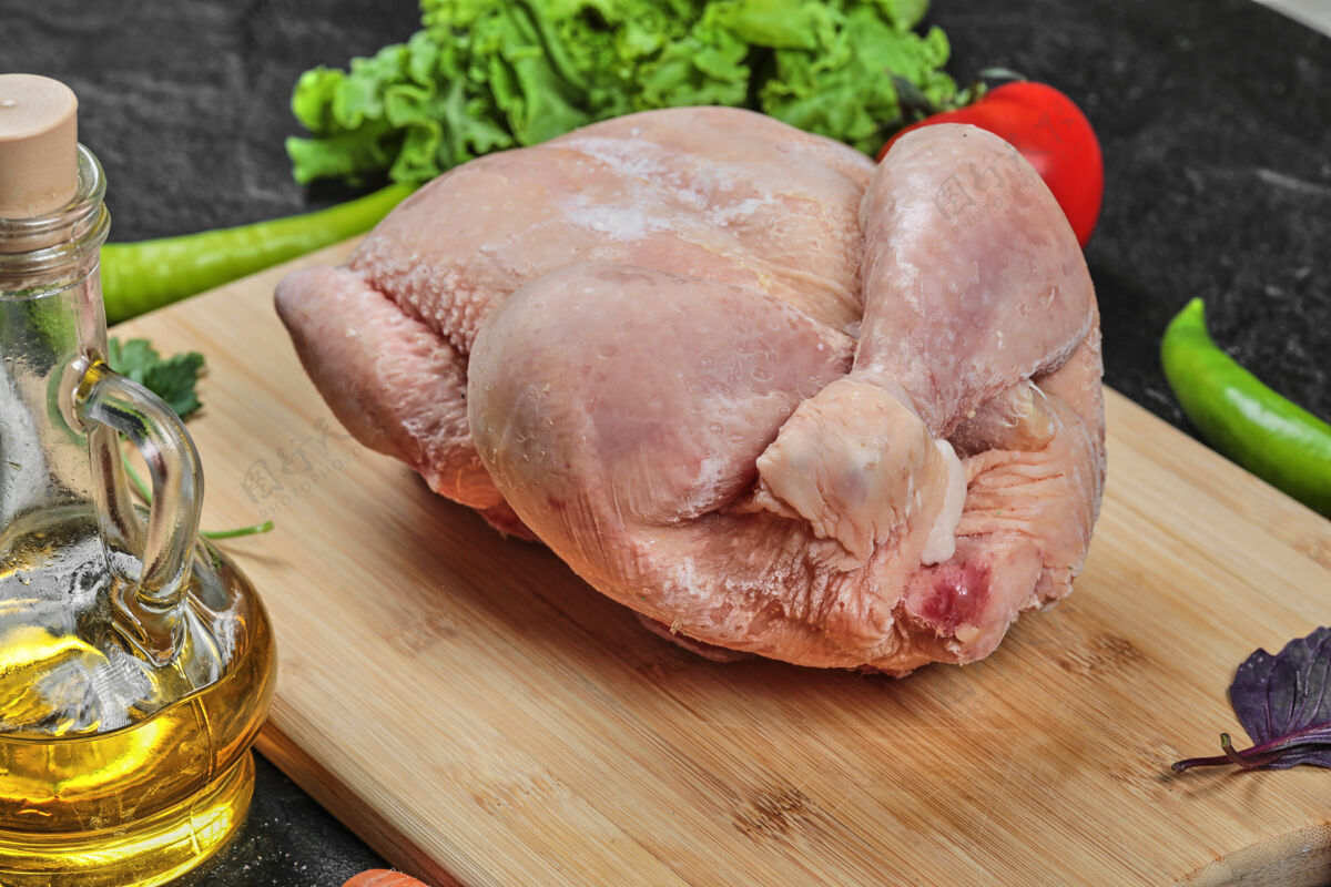 有机生的整只鸡放在木板上 油和西红柿油西红柿家禽
