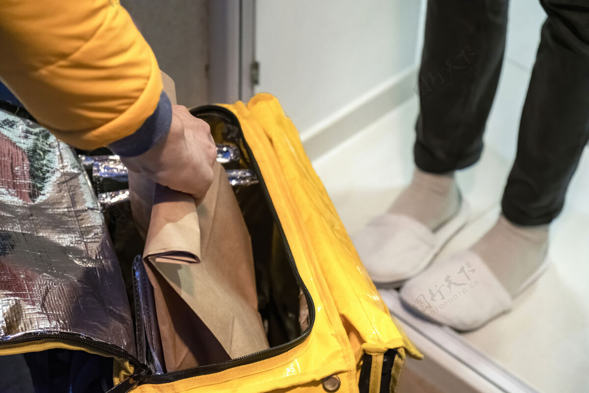 人送货员打开黄色背包 拿着一个带订单的包 腿是别人的经济服务冠状病毒