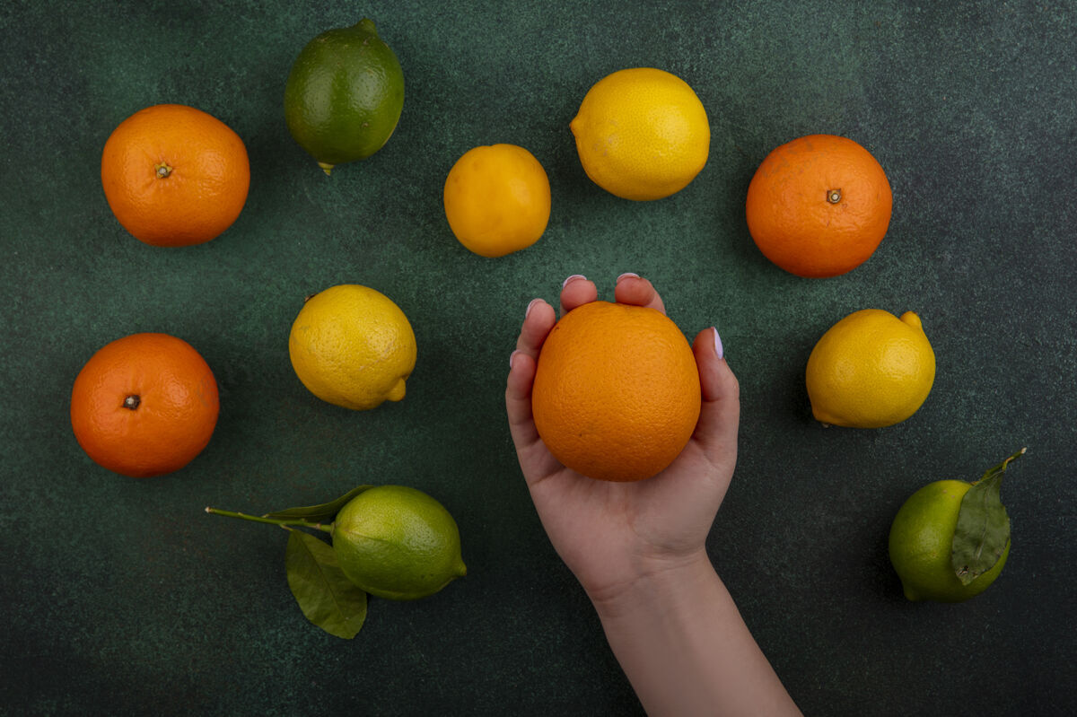 酸橙色俯视图：在绿色背景上拿着橘子 柠檬和酸橙的女人绿色视野橙色