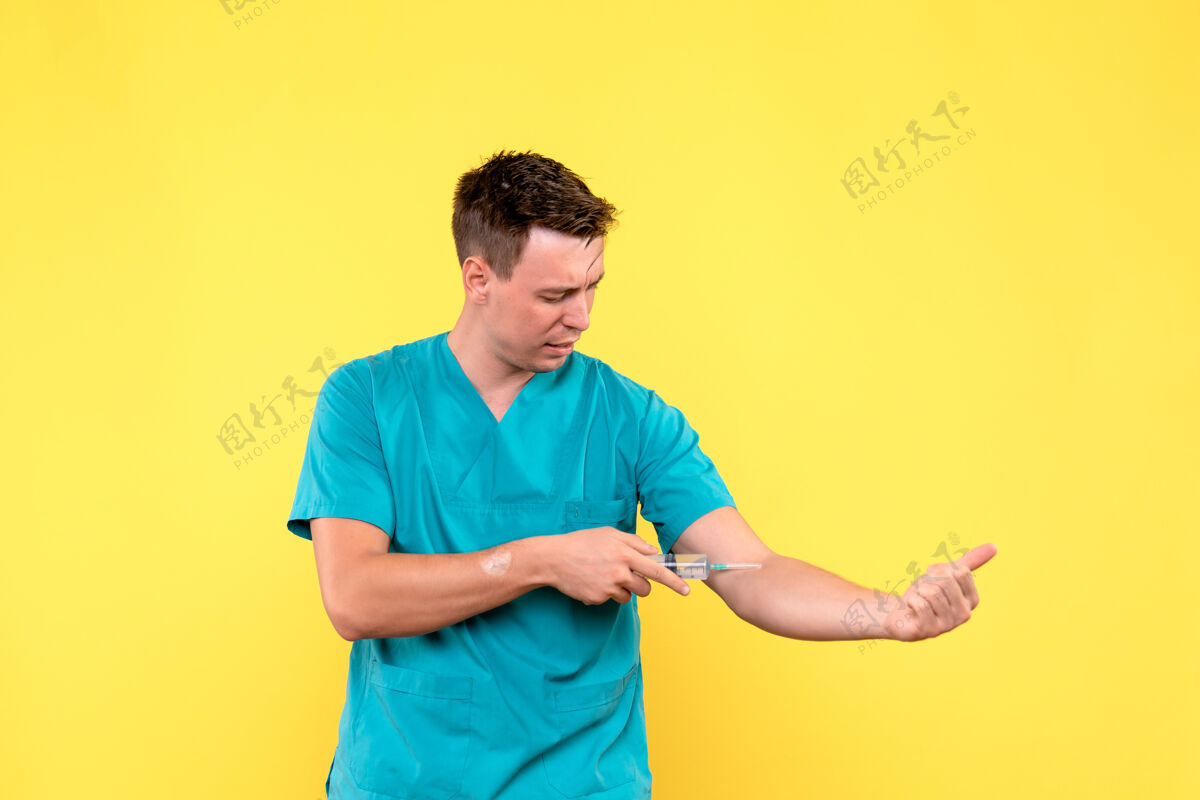 帅哥黄色墙壁上使用巨大注射剂的男医生的正视图人男性设备