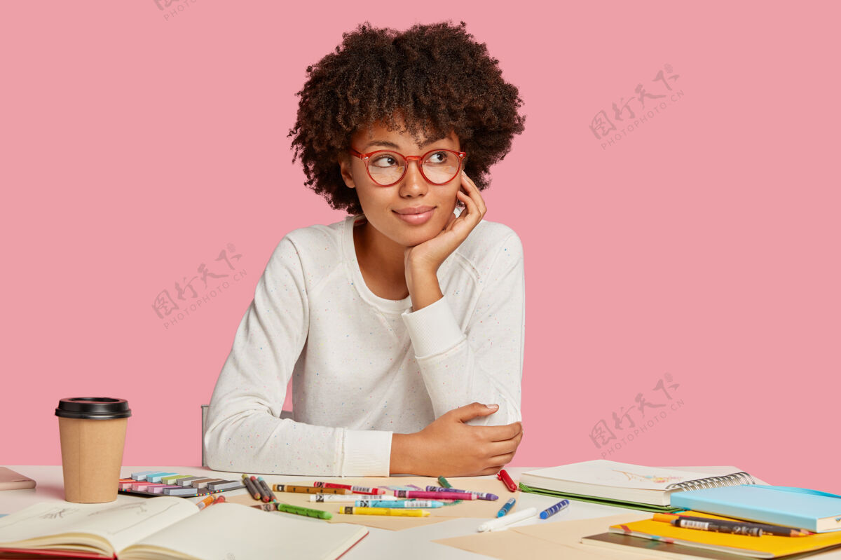 成年人忧郁的黑皮肤学生独自学习艺术 喜欢画画 戴着眼镜 表情深邃 头发蓬松 用空白纸做记事本 隔离在粉红色的墙上计划建筑师项目