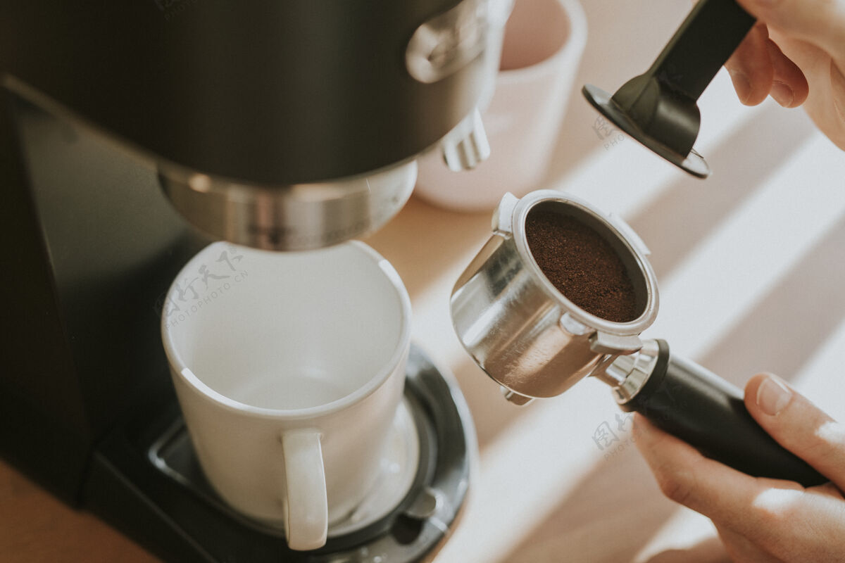 粉末咖啡师在咖啡机的过滤器里压榨磨碎的咖啡饮料准备卡布奇诺