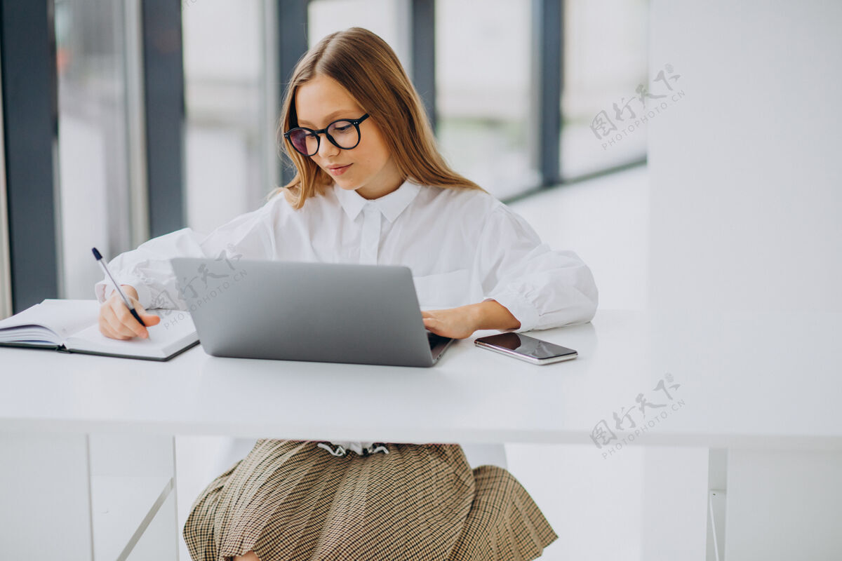 休闲可爱的女孩在家里用电脑学习计算机可爱坐着
