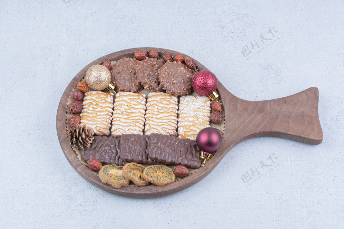 节日各种饼干 干果和圣诞球放在木板上玫瑰果巧克力冰