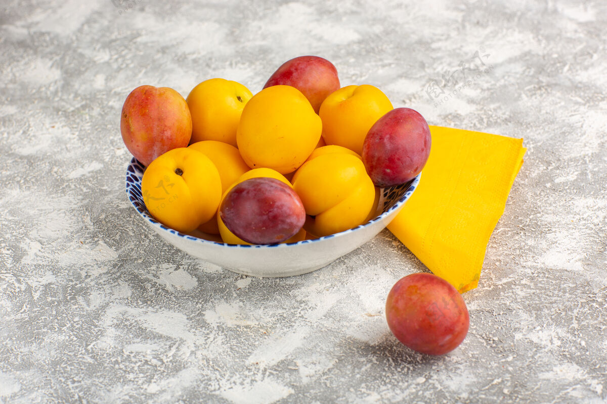 芒果正面图新鲜甜杏黄色水果盘内与李子在白色表面杏内可食用水果