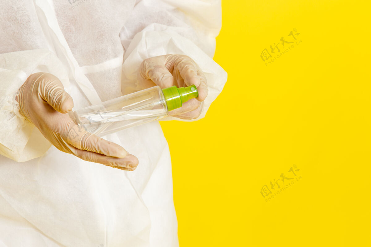 医学正面图身穿特殊防护服的男科学工作者手持喷雾瓶在淡黄色的表面上医疗科学西装