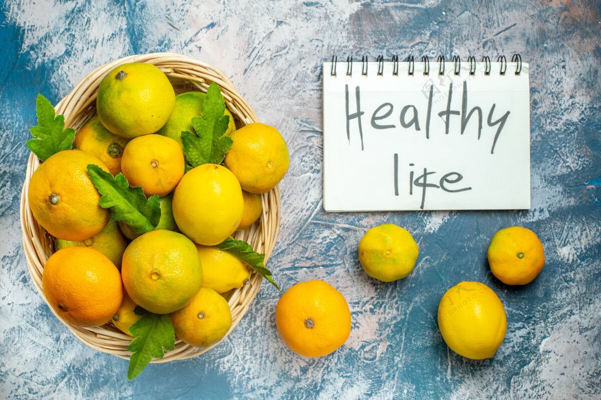 观点顶看柳条篮上的新鲜柑桔健康生活写在蓝白色的记事本上写作维生素柠檬