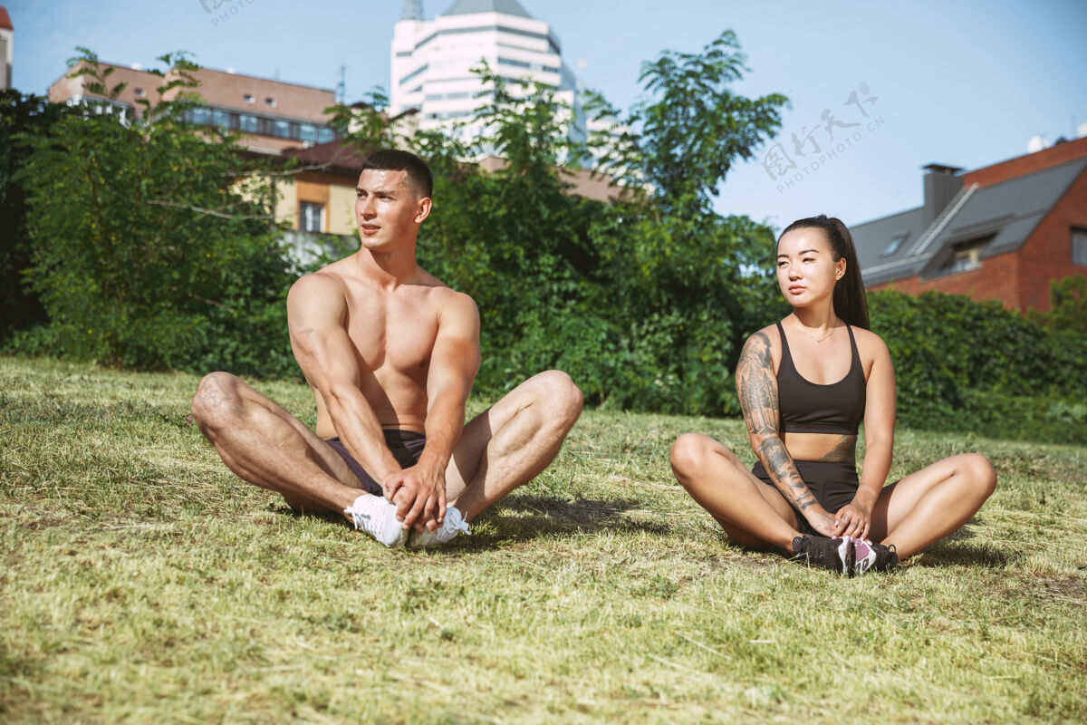 肌肉一个肌肉发达的运动员在公园里锻炼身体体操 训练 健身 柔韧性锻炼夏日城市里阳光明媚的日子背景场积极健康的生活方式 青春 瑜伽 健美英俊活动运动