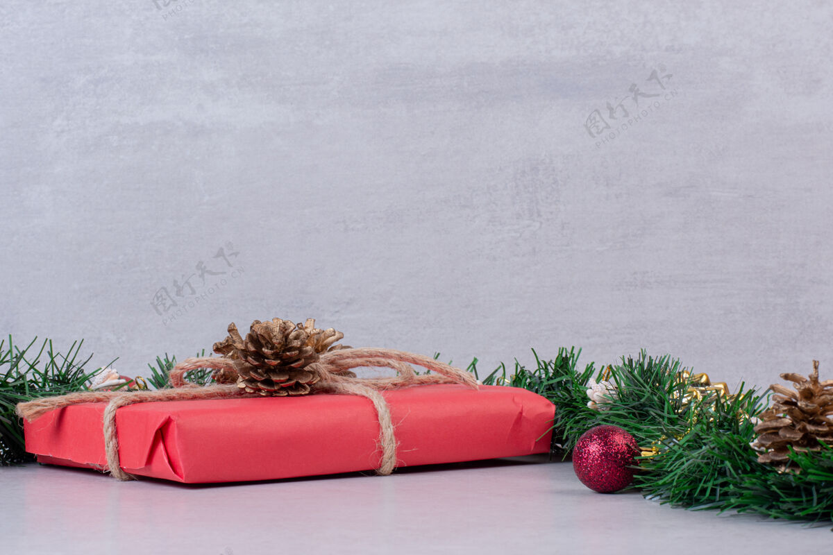 节日圣诞松果玩具与灰色表面上的红色盒子玩具圣诞装饰松果