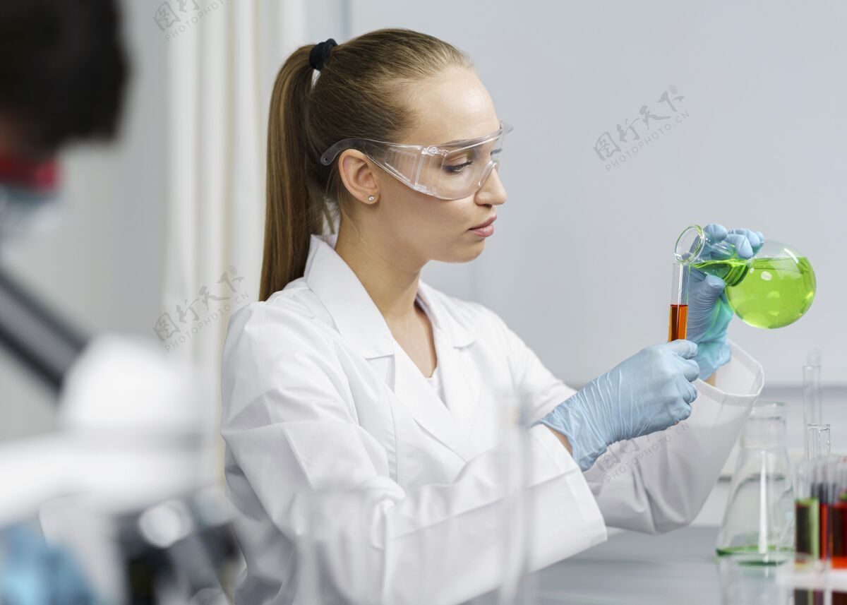 女实验室里的女研究员的侧视图 带着试管和安全眼镜女研究水平