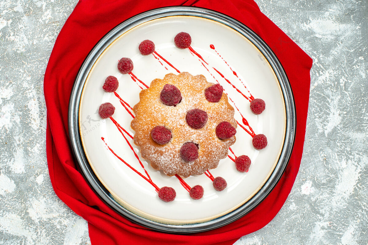 甜点白色椭圆形盘子上的浆果蛋糕 灰色表面上的红色披肩碗浆果布丁