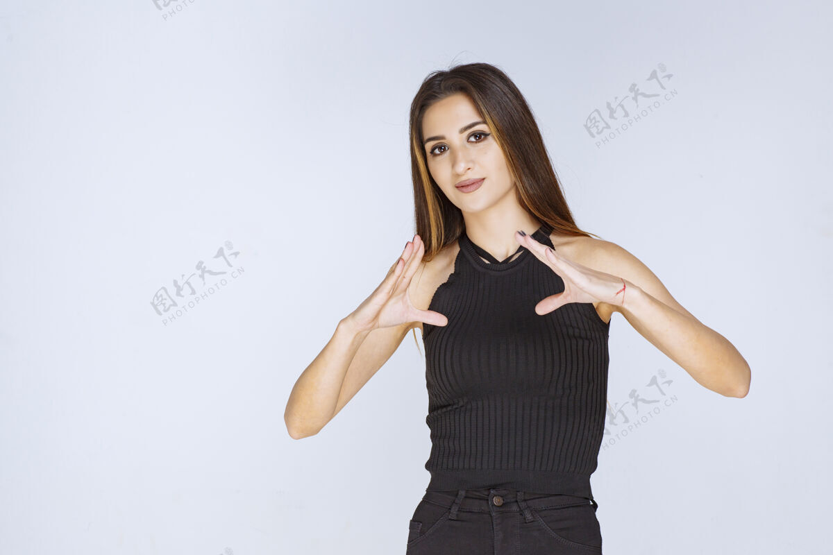 年轻穿黑衬衫的女人在做三角牌女性信仰符号