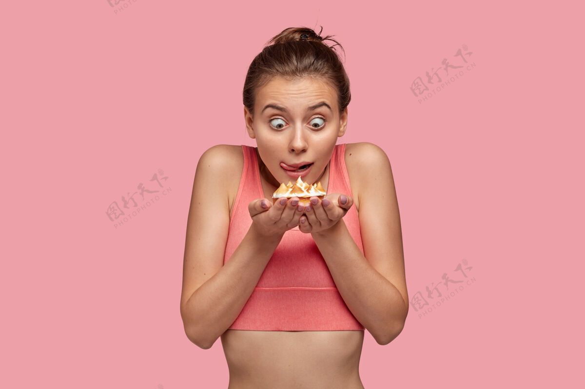 私人教练震惊的女人用窃听器的眼睛盯着蛋糕照片健身衣服