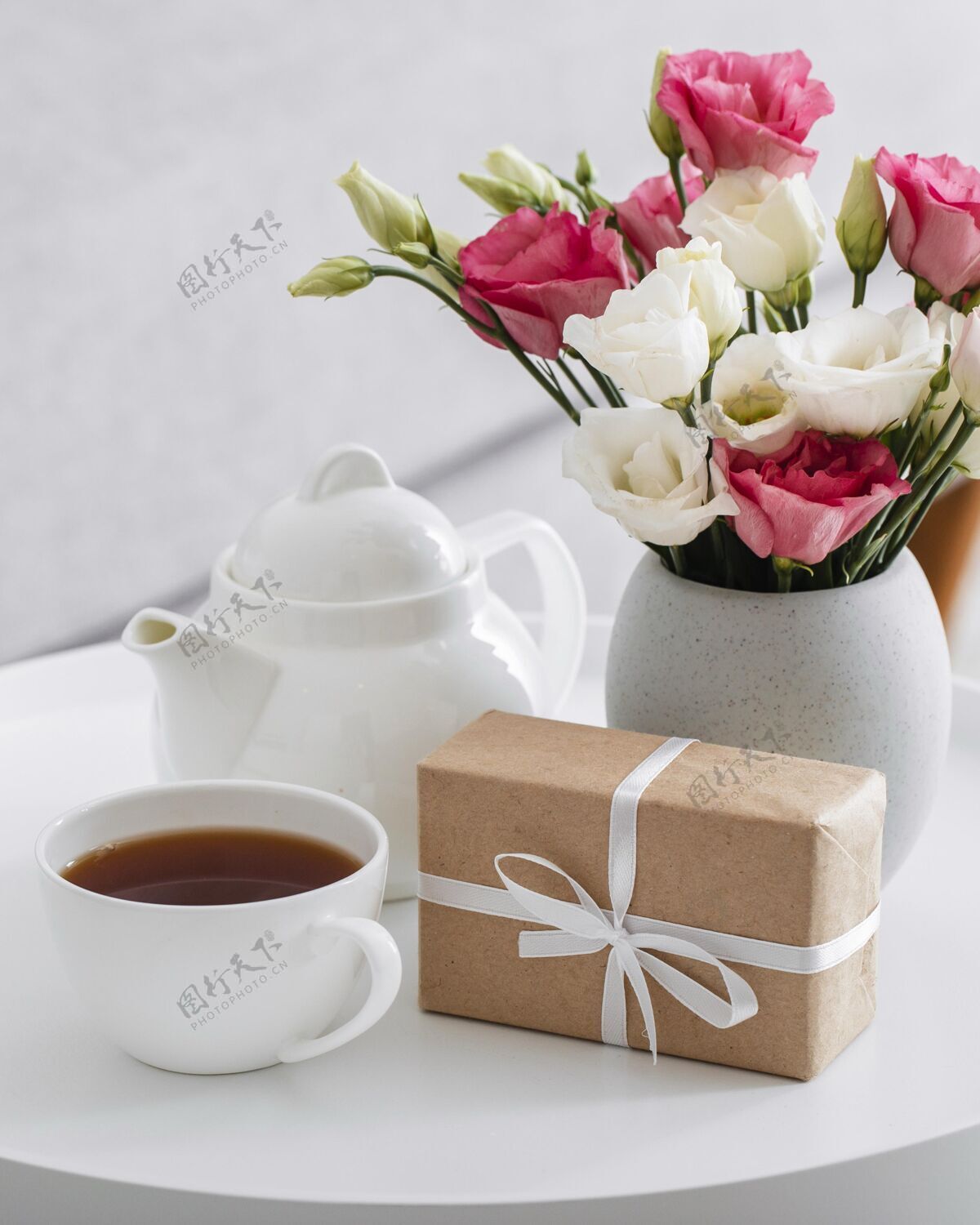 花束花瓶里放着一束玫瑰 旁边是一份包装好的礼物和一杯茶美丽植被季节