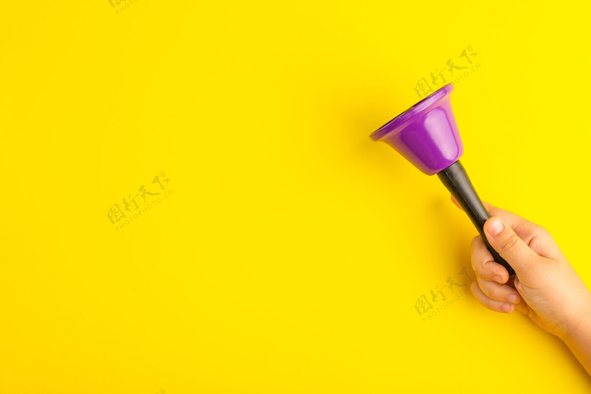 铃铛正面图黄色表面上拿着紫色铃铛的小孩孩子手握铅笔