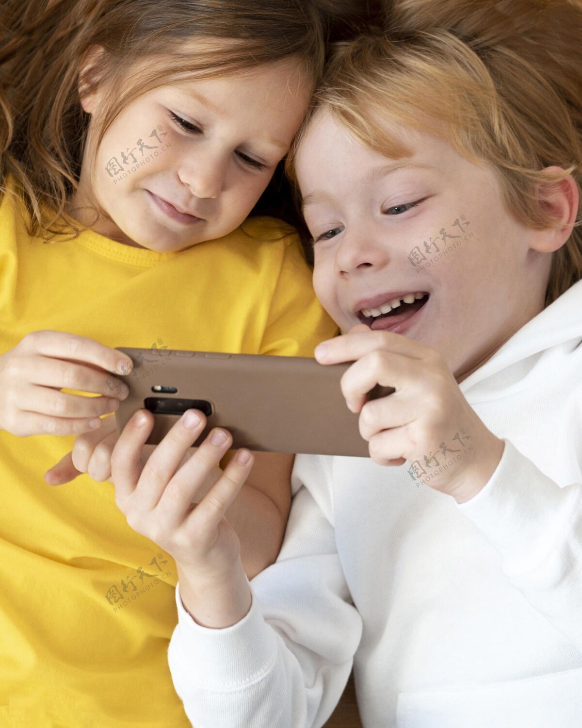 娱乐笑脸小孩一起使用智能手机的顶视图消遣业余爱好设备