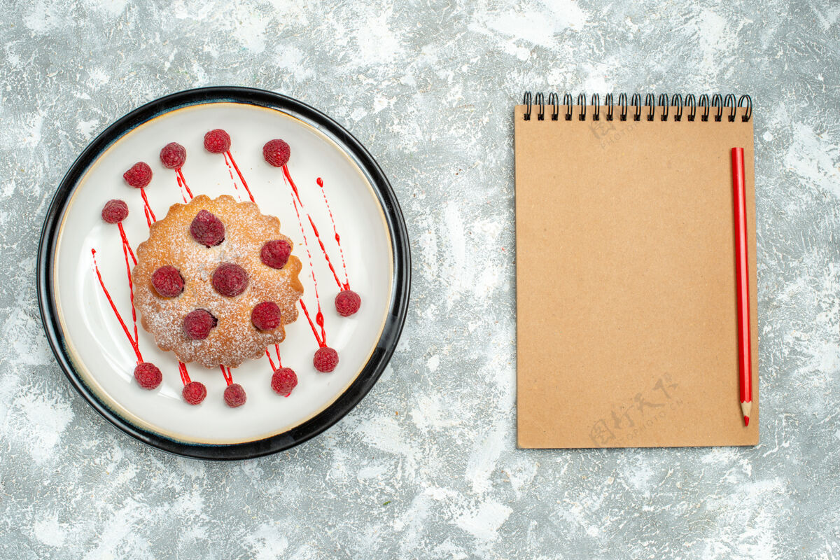 观俯视图白色椭圆形板上的浆果蛋糕笔记本红色铅笔灰色表面化妆品Berrycake粉