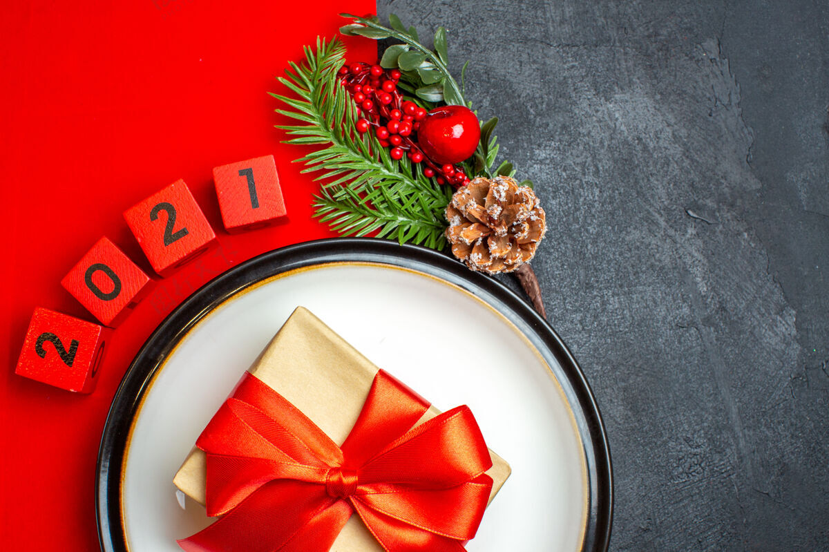 圣诞节新年背景用漂亮的礼品在餐盘上装饰配件杉木枝和数字 在一张红色餐巾上放在一张黑色的桌子上半拍照片数字餐盘餐巾