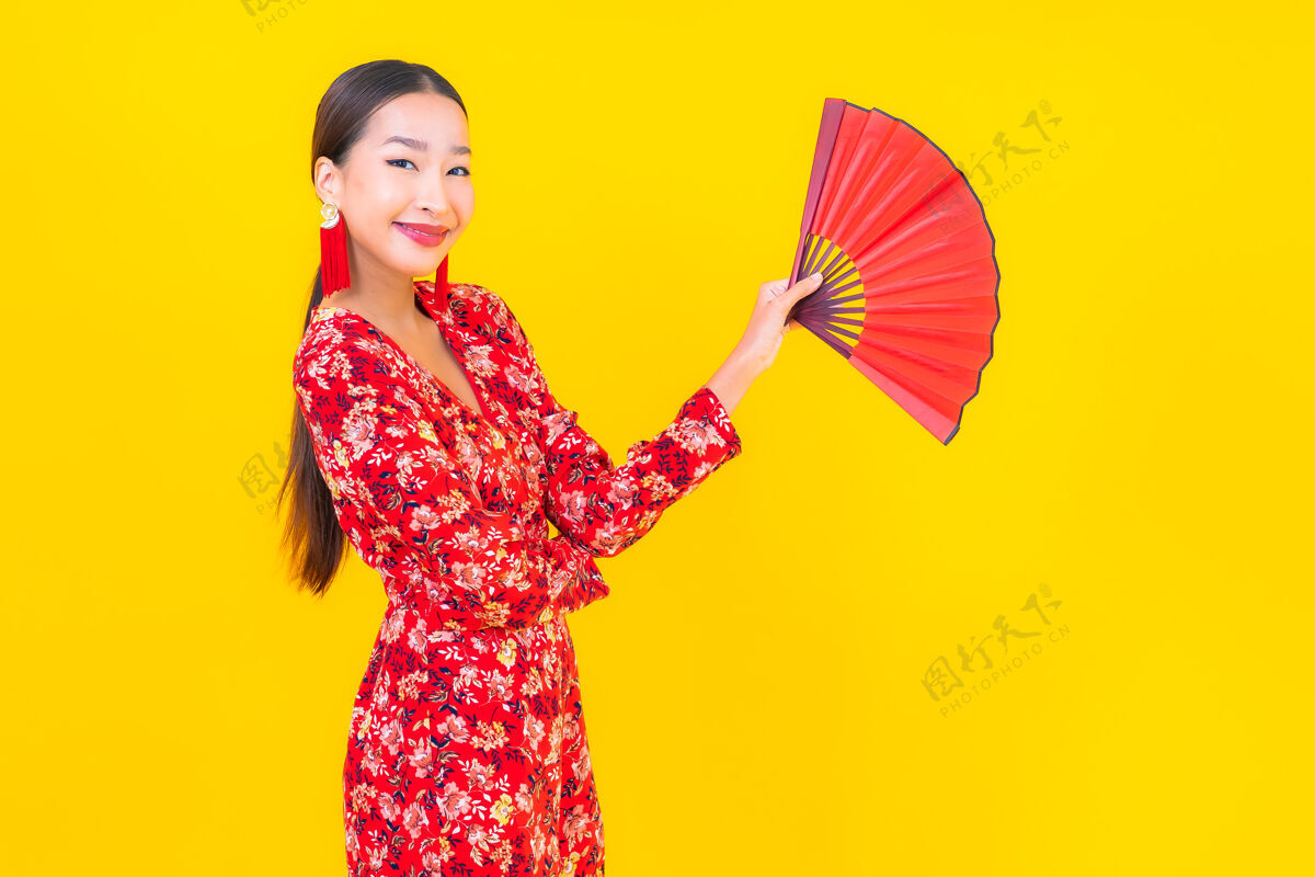 春天美丽的亚洲年轻女子在彩色墙上的中国新年概念中的微笑手历史金融