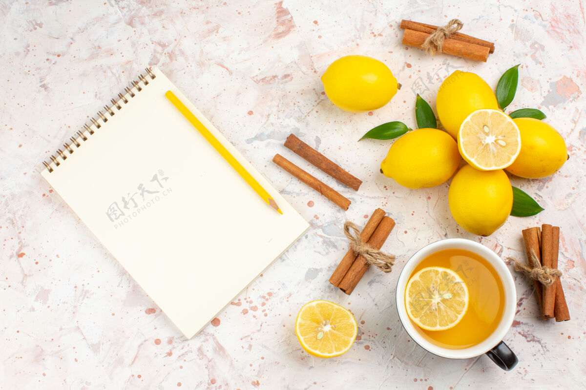 茶顶视图新鲜柠檬切柠檬肉桂棒一杯柠檬茶笔记本上明亮的孤立表面笔记本早餐杯子