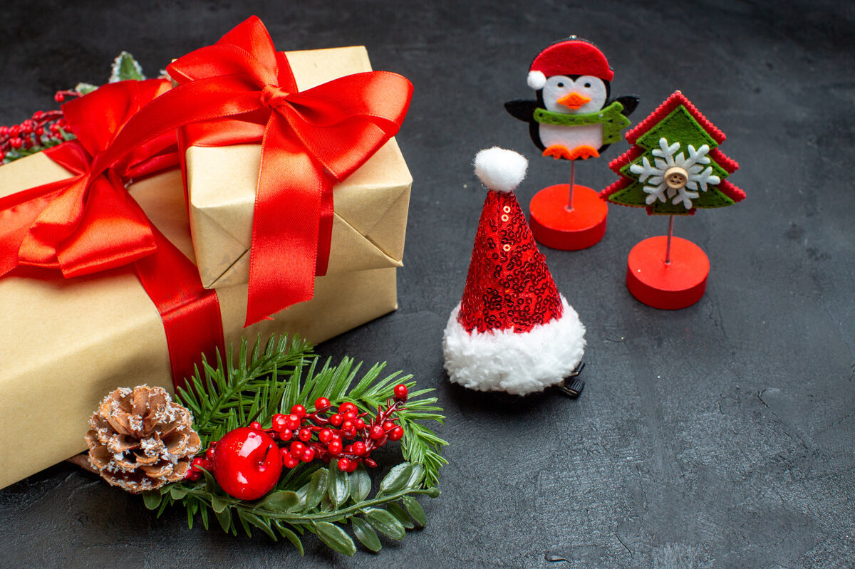 壁板侧视图的圣诞心情与蝴蝶结形彩带和杉木枝装饰配件圣诞老人帽针叶树锥上一个黑暗的背景美丽的礼物圆锥体树枝风景