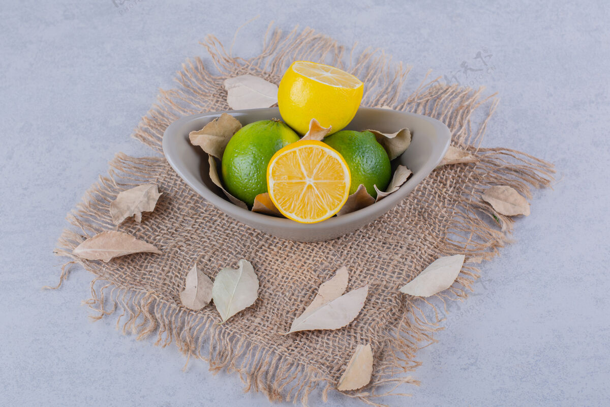 粗麻布石桌上放着一碗新鲜多汁的柠檬健康有机成熟