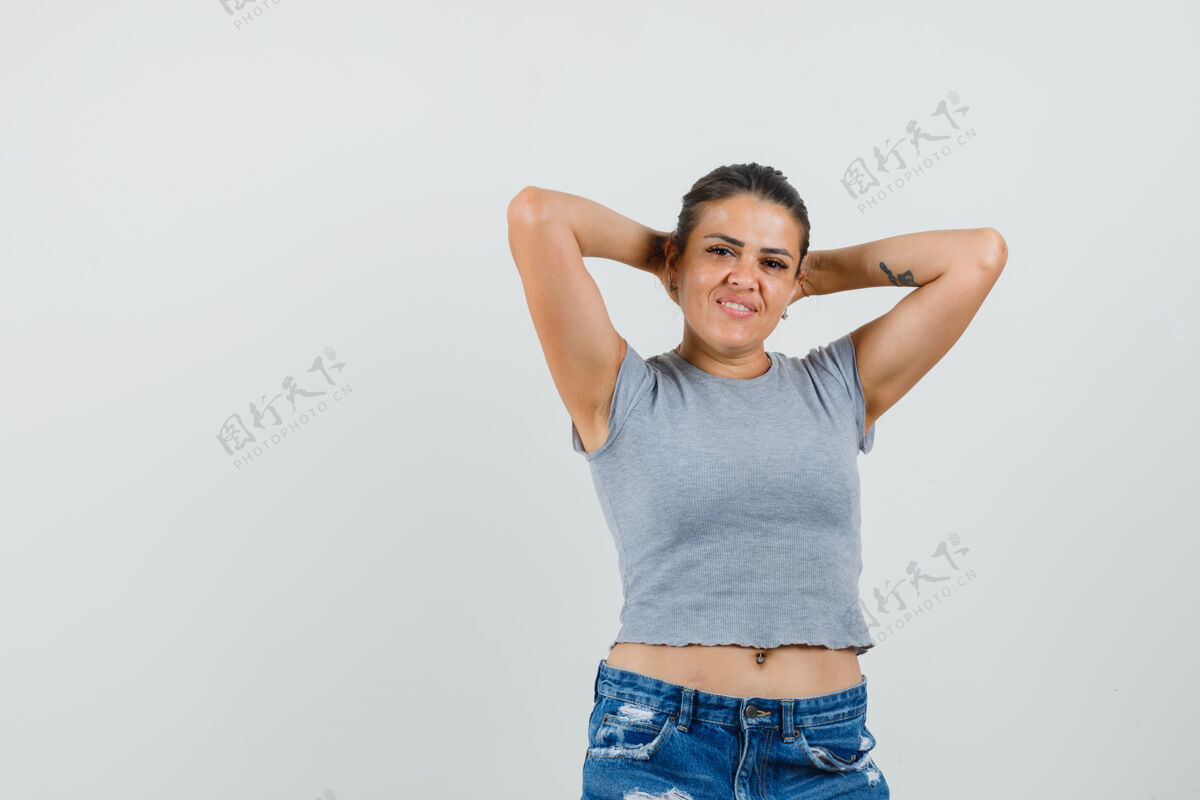 黑发年轻女性手牵手在头后 穿着t恤 短裤 看上去很放松漂亮短裤时尚