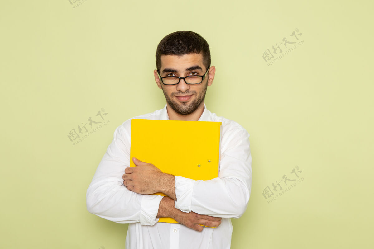 办公室身穿白衬衫的男办公室工作人员手持黄色文件 微笑着站在绿色墙上工人工作男人