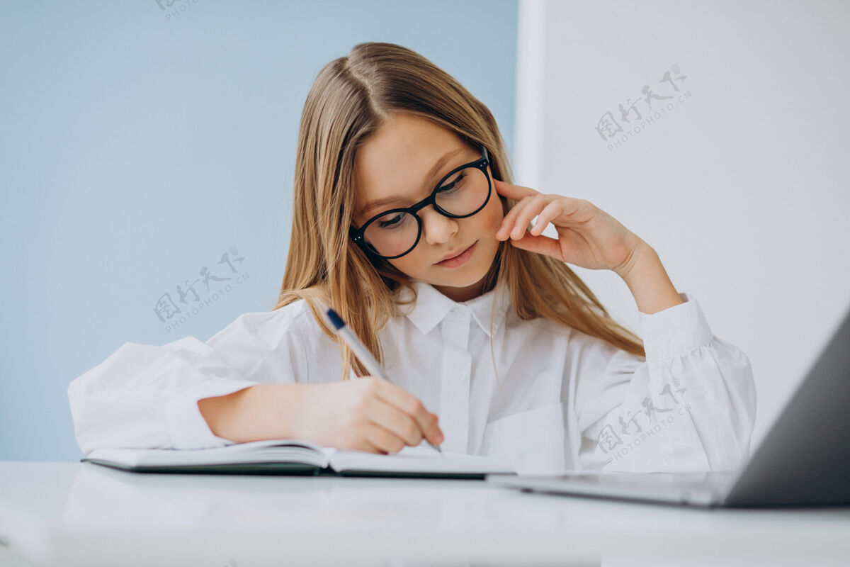 年轻可爱的女孩在家里用电脑学习学校书桌学生