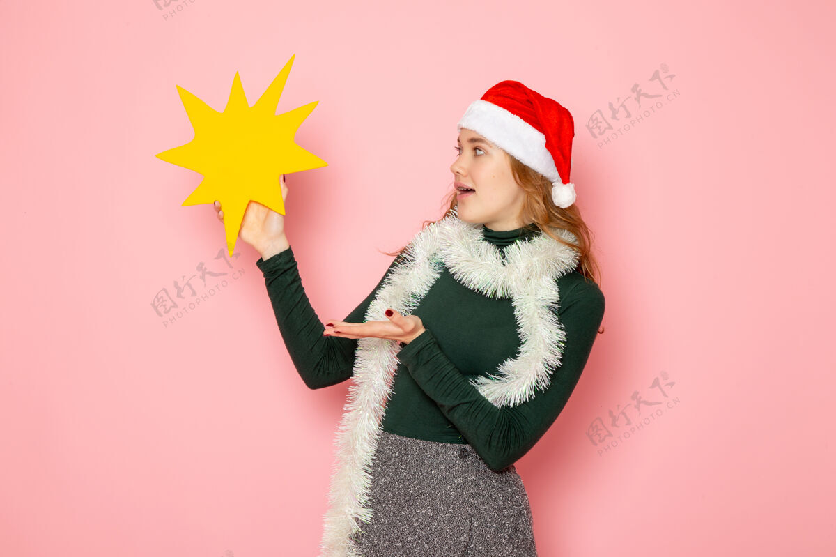 身材正面图年轻女性手持粉色墙壁上的黄色大人物彩色模特节日圣诞新年感慨帽子颜色年轻的女性
