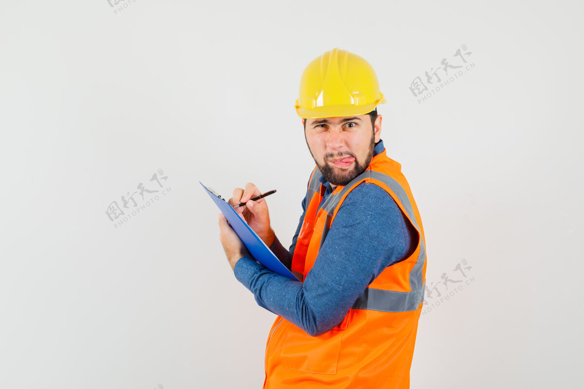 职业穿着衬衫 背心 头盔的年轻建筑工人在剪贴板上做笔记工程师头盔工作