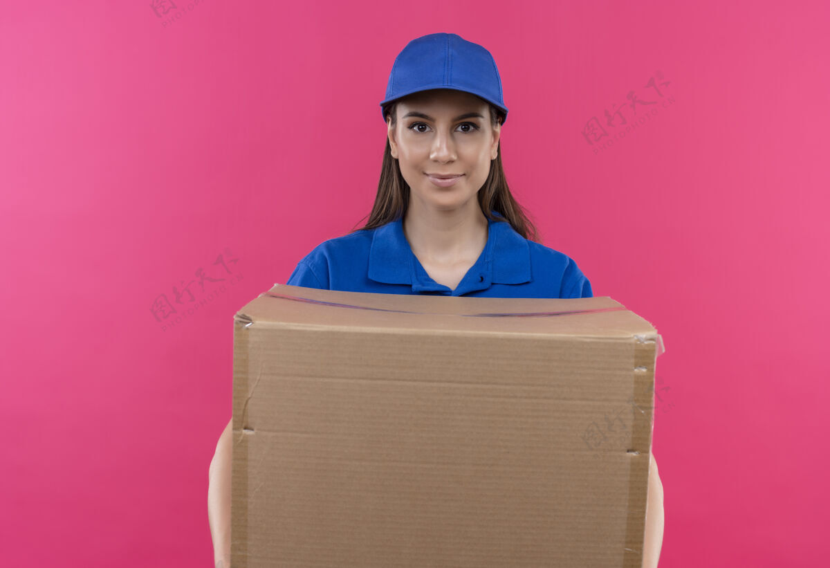 粉色身穿蓝色制服 头戴帽子的年轻送货女孩拿着大礼盒 神情严肃自信地看着镜头表情制服包装