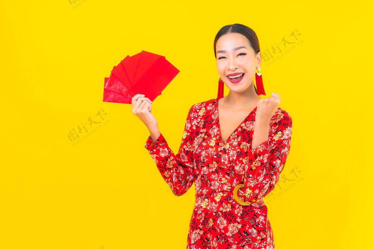 人类在黄色的墙上画一幅美丽的亚洲年轻女子拿着红包传统女孩运气