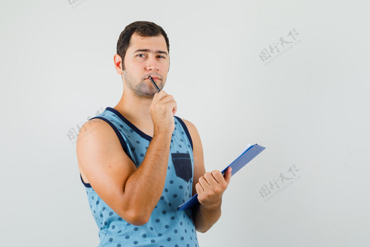 男穿着蓝色单品的年轻人手里拿着写字板和笔 神情沉思成功自信胡须