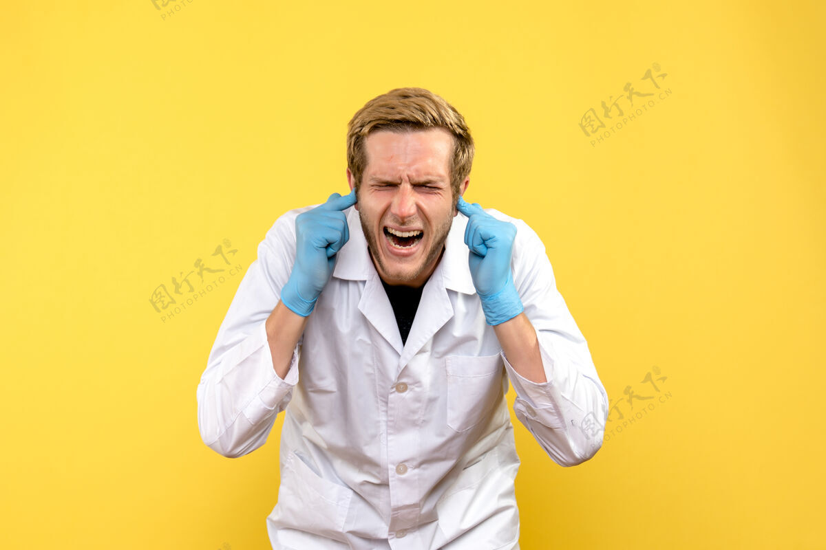 实验室外套前视图男性医生在黄色背景下用耳朵堵住了人的耳朵外套耳朵专业