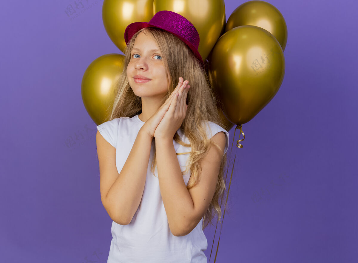 一起戴着节日礼帽的漂亮小女孩 一群巴龙手牵手 微笑着等待惊喜 紫色背景上站着生日派对的概念举行微笑手掌