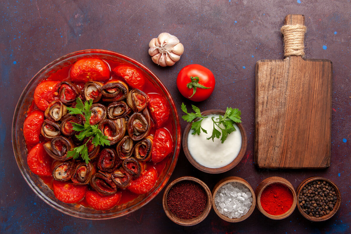 西红柿俯瞰煮熟的蔬菜餐美味的西红柿和茄子与调味品在黑暗的表面烹饪盘子美味