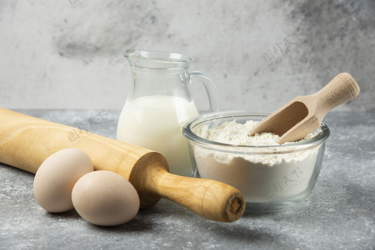 别针一碗面粉 鸡蛋 牛奶和擀面杖放在大理石桌上擀面杖勺子生的