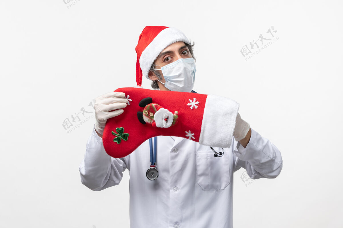 制服正面图男性医生拿着白色办公桌上的大节日袜子病毒柯维德-假日微笑冠状病毒男人
