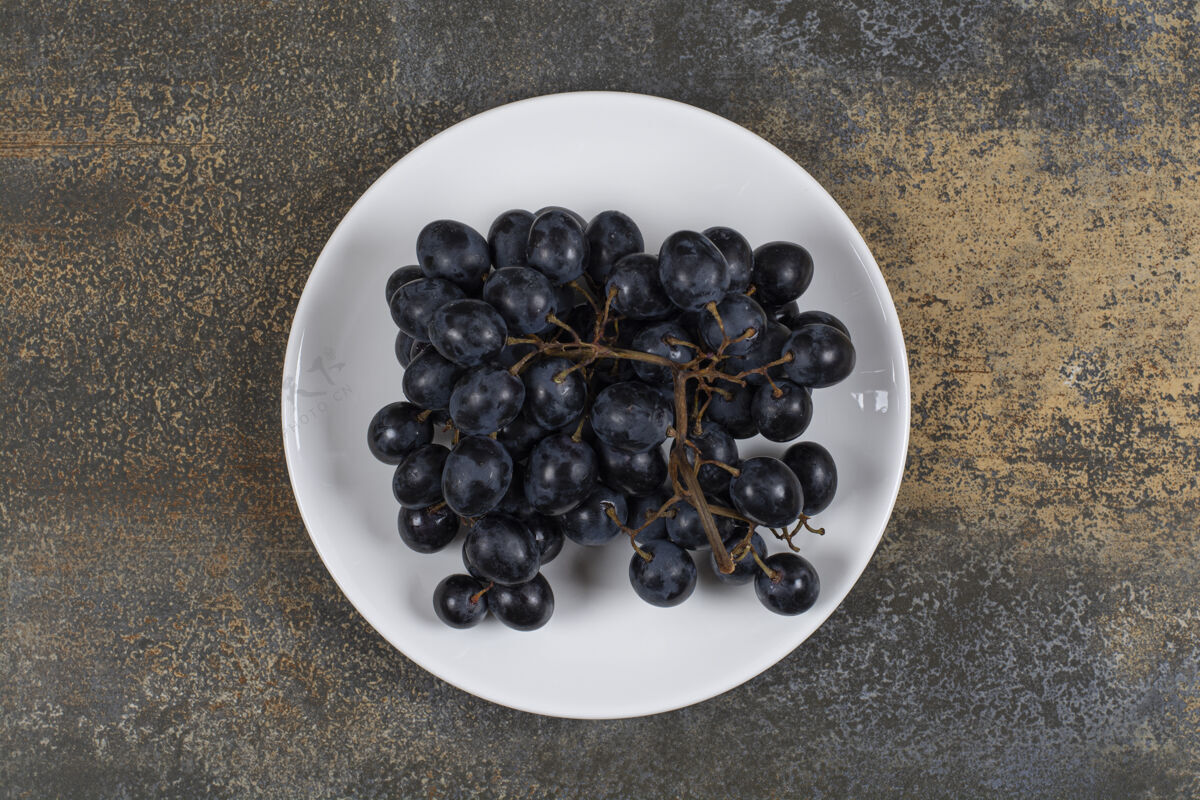 成熟白色盘子上的一簇黑葡萄有机可口新鲜