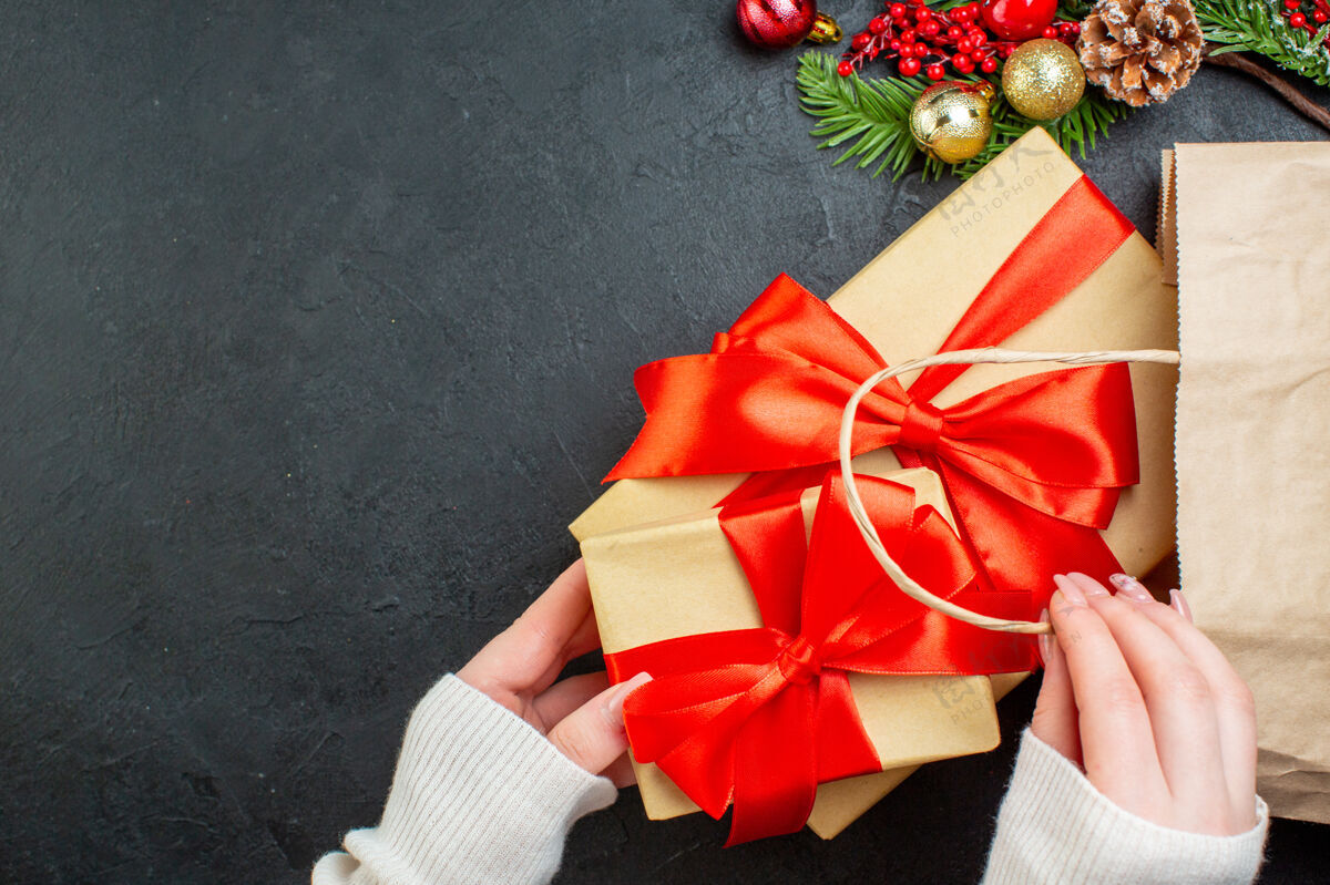 圣诞手从黑色背景的袋子里拿出一个漂亮的礼盒的特写镜头丝带礼品轮子