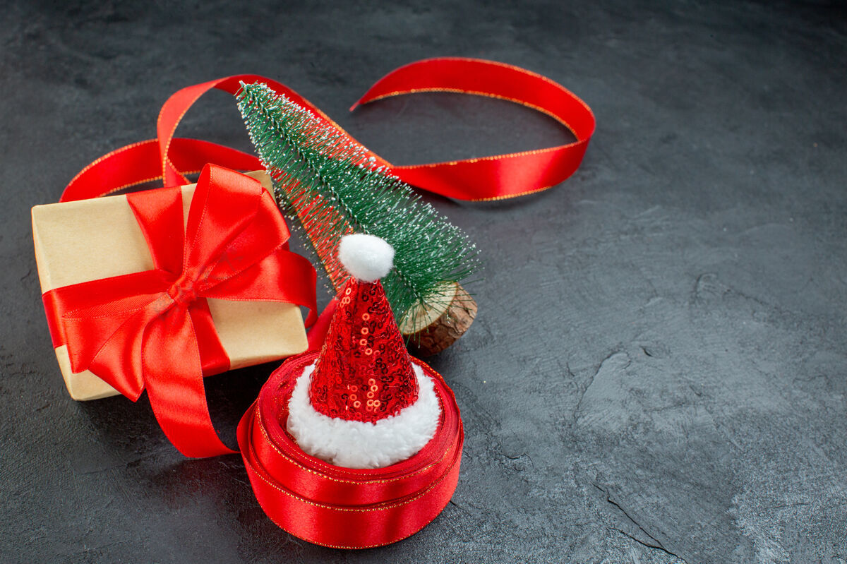 甜点俯瞰圣诞老人帽子上的一卷丝带和美丽的礼物圣诞树在黑暗的背景景观鲜花圣诞节