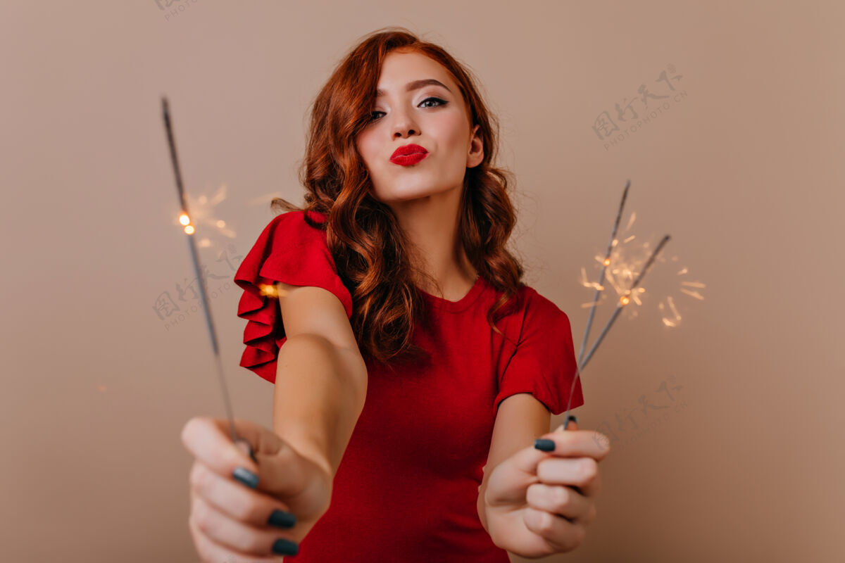 微笑浪漫的红发女孩在新年派对上手持孟加拉灯迷人的女模特带着火花庆祝圣诞节新年派对表情成人