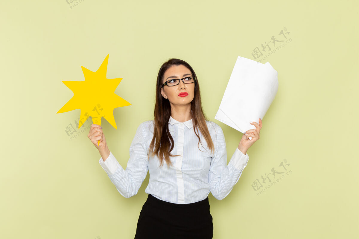 女人身穿白衬衫和黑裙子的女上班族的正面图 绿色墙上拿着纸和黄色的牌子办公室家庭主妇抱