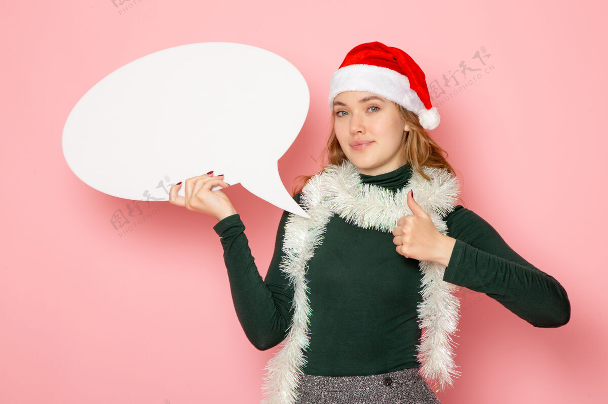 漂亮正面图年轻女性手持粉色墙上的白色大招牌圣诞新年造型节日色彩感慨快乐风景圣诞