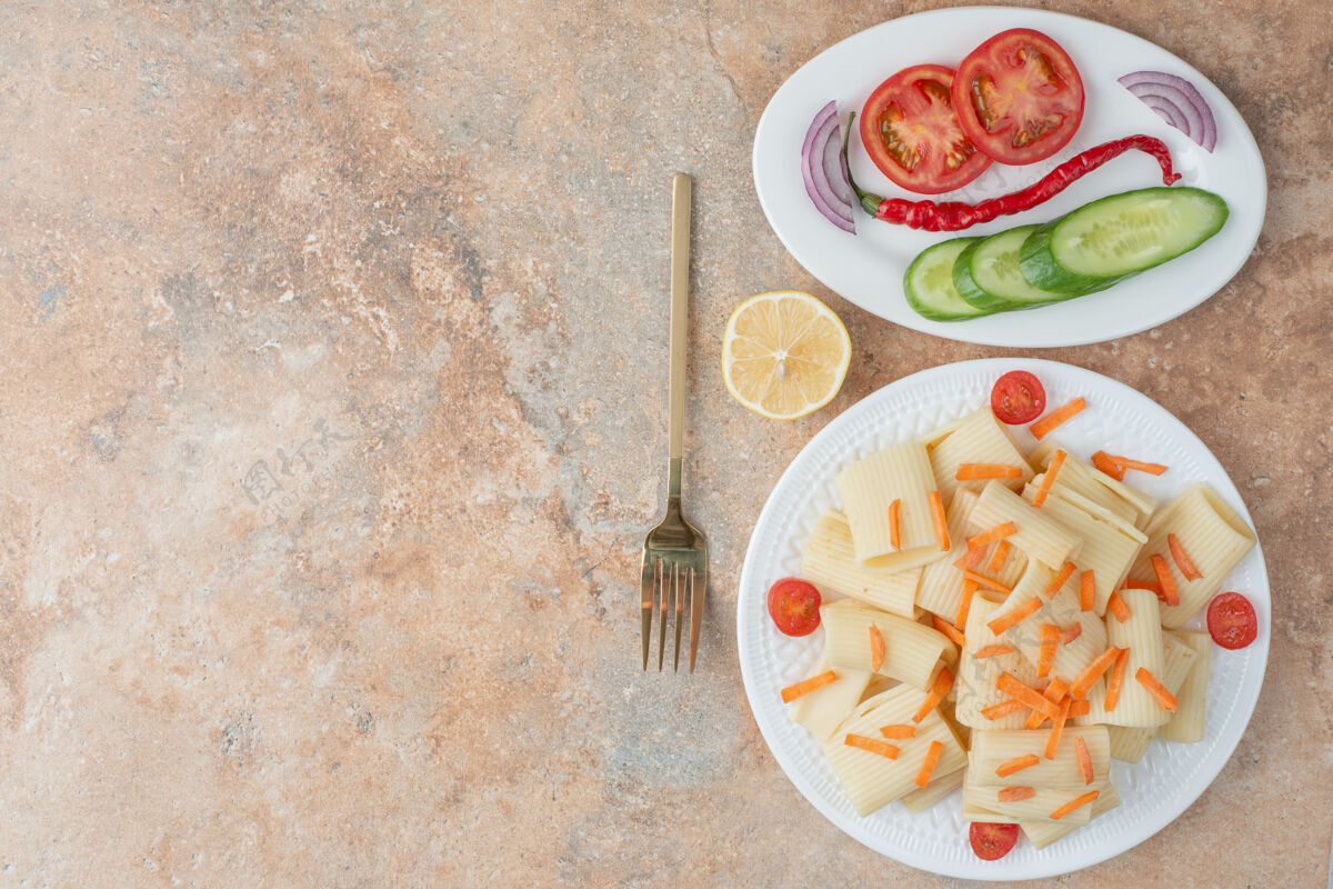 切片胡萝卜通心粉 番茄樱桃 黄瓜和柠檬片放在白色盘子里美味番茄食物